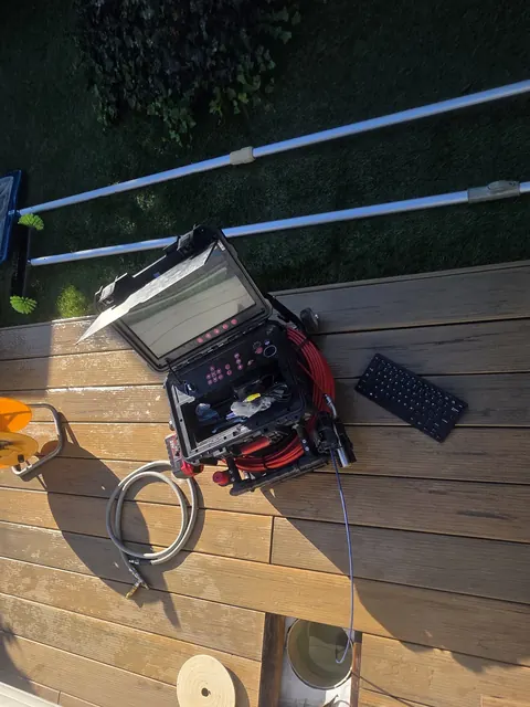 Caméra d'inspection posée sur une terrasse en bois, regard ouvert
